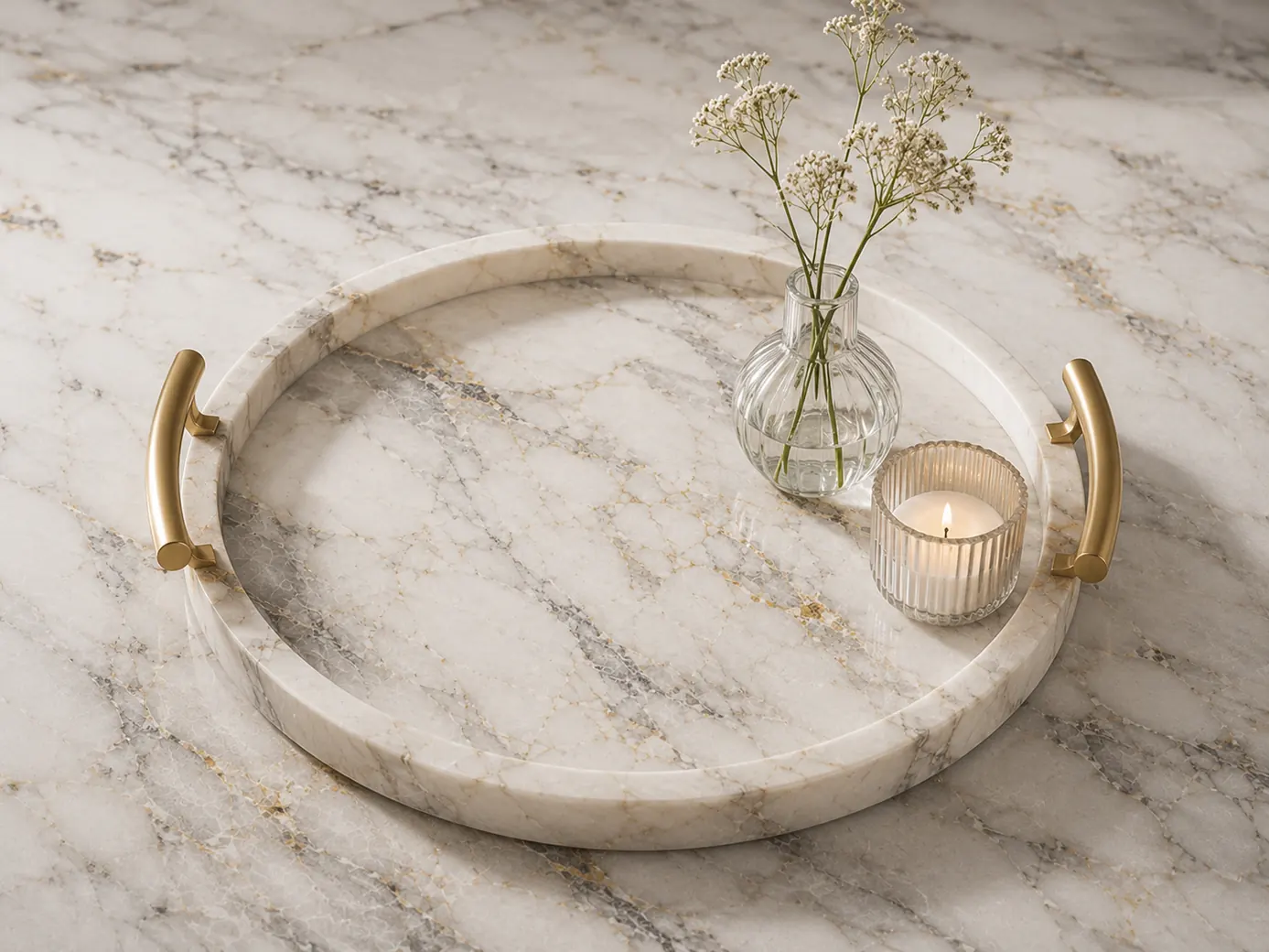 Round white marble tray with gold handles on a matching marble surface